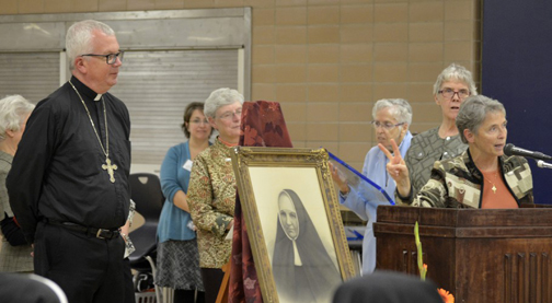 Bishop Donald J. Hying accepts an award and a $1,900 donation to the Diocese of Gary by Sister Michele Dvorak (at podium) and other members of the Poor Handmaids of Jesus Christ during the religious order's Coming Home NWI weekend event Oct. 22-23 at Bishop Noll Institute in Hammond. The donation will be used, Bishop Hying has announced, to establish a Mercy Fund endowment to award grants to agencies and organizations performing Corporal and Spiritual works of mercy. (Provided photo)